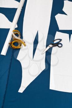 tailor tools and paper sample of dress on blue fabric for dress cutting
