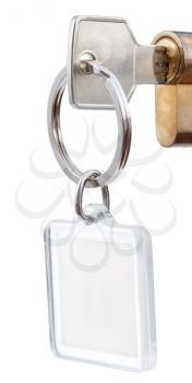 door key with square keychain in cylinder lock close up isolated on white background