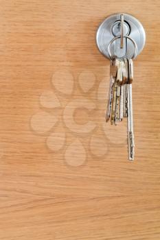 bunch of home keys in lock of wood door close up