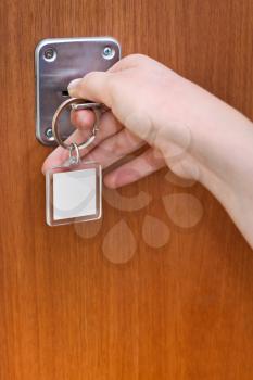 opening home door by key with blank keychain close up