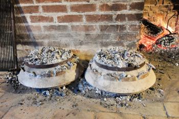 cooking of traditional dalmatian meal Peka in metal pots under burning coals