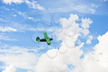 small green plane flying in blue sky in summer day