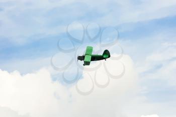 small green agriculturial aircrafte flying in blue sky in summer day