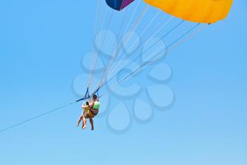couple people parasailing on parachute in blue sky in summer day