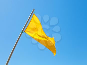 Beach safety warning yellow flag with blue sky background