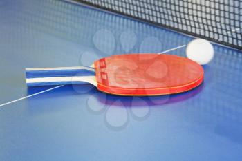 red paddle, tennis ball on blue ping pong table close up