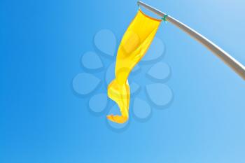 Beach safety yellow flag with blue sky background