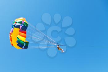 woman parasailing on parachute in blue sky in summer day