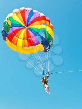 girl parascending on parachute in blue sky in summer day