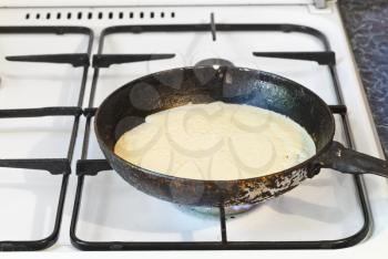 cooking pancake on frying pan on gas stove