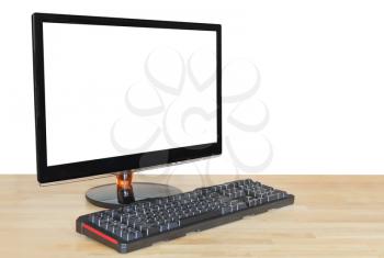 side view of computer black widescreen display with cut out screen and keyboard on wooden table isolated on white background