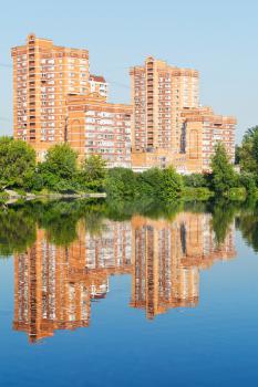 brick apartment houses along city pond in sunny summer day
