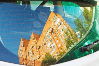 reflection of urban apartment house in car window in sunny day