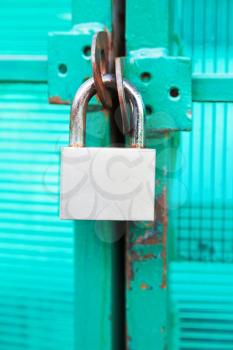 green door locked with steel padlock close up