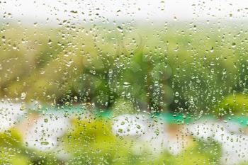 raining outside window - rain drops on window glass in summer day