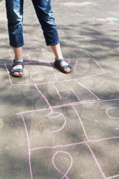 girl playing in hopscotch outdoors in sunny day