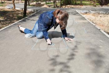 girl drawing hopscotch outdoors in sunny day