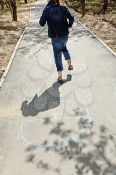 girl hopping in hopscotch on urban alley in sunny day