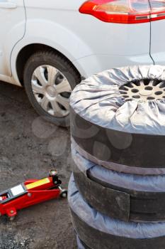 seasonal replacement of car tyres with jack outdoors - set of summer tyres