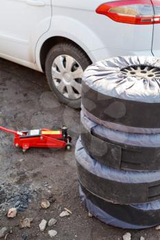 seasonal replacement of car tyres with jack outdoors - preparation for repair