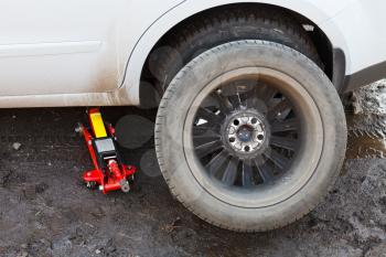 seasonal replacement of car tires with jack outdoors - preparing wheel