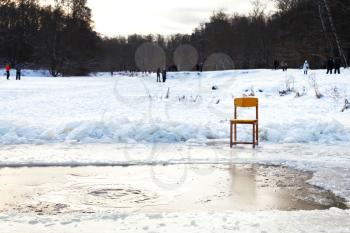icebound chair near opening water in frozen lake after orthodox epiphany holiday in cold winter evening