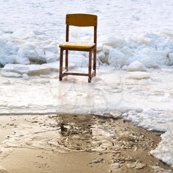 icebound chair on edge of ice-hole in frozen lake in winter