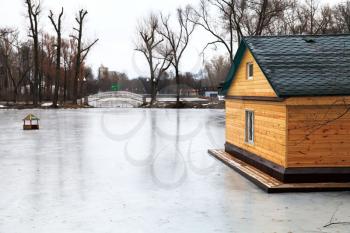 frozen lake with bridge and wooden house on winter day
