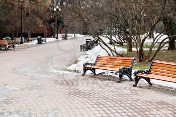 empty wooden benches in city park on cold winter day