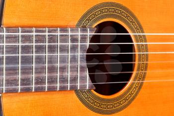 fingerboard and sound hole of classical acoustic guitar with six nylon strings close up