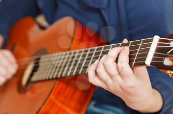 girl plays on classical acoustic guitar close up