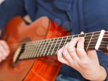 woman plays on classical acoustic guitar close up