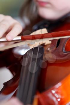 child plays on violin by bow close up