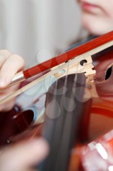 child plays on fiddle by bow close up