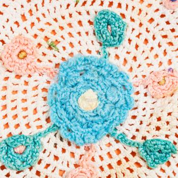 vintage knitting craftsmanship - flower ornament by crochet needlework close up