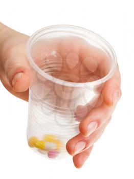 plastic cup with portion of pills in hand isolated on white background