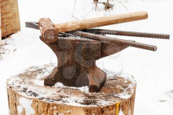 anvil with blacksmith tongs and hammer in old abandoned village smithy in winter