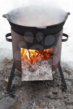 cooking stew on outdoor mobile brazier in winter