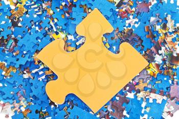 one big yellow piece on pile of disassembled little blue jigsaw puzzles