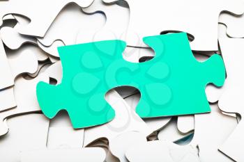 one green piece of puzzle on pile of white jigsaw puzzles