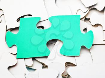 separate green piece of puzzle on pile of white jigsaw puzzles