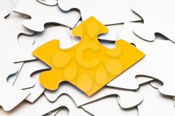 separate yellow piece of puzzle on pile of white jigsaw puzzles