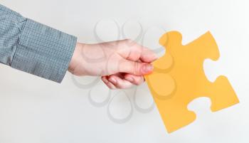 yellow puzzle piece in female hand on grey background