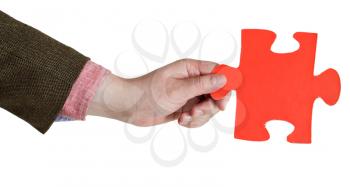 male hand holding big red paper puzzle piece isolated on white background