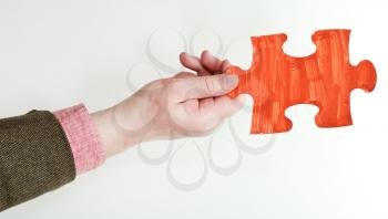 red painted puzzle piece in male hand on grey background