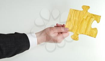yellow painted puzzle piece in male hand on grey background