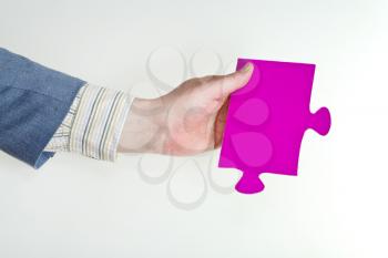 pink puzzle piece in male hand on grey background