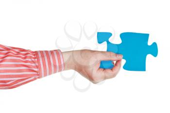 male hand holding big blue paper puzzle piece isolated on white background
