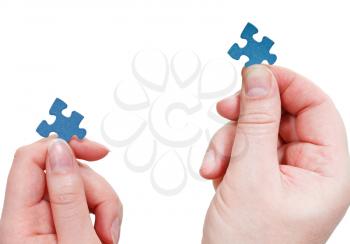 male and female hands with little puzzle pieces close up isolated on white background