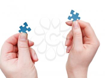 male and female hands with blue puzzle pieces close up isolated on white background